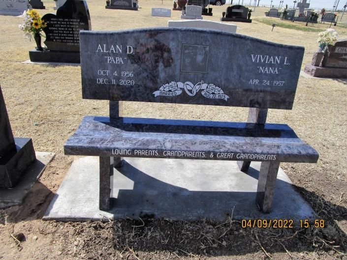 Black granite memorial bench gravestone in a cemetery, with engraved names and decorative flowers.