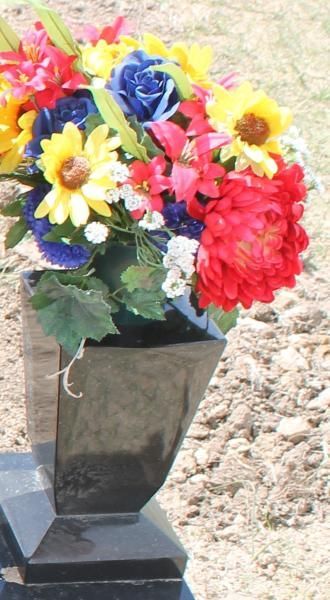 Bright mixed flower bouquet in a black vase on a stone surface