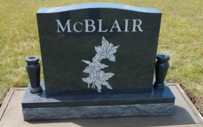 McBlair gravestone with floral engraving on a dark granite monument in a grassy cemetery