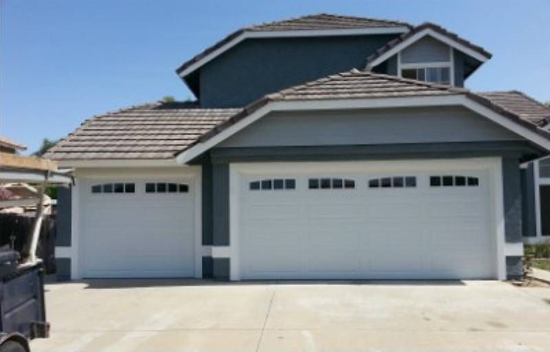 A Large House with Two Garage Doors and A Golf Cart Parked in Front of It