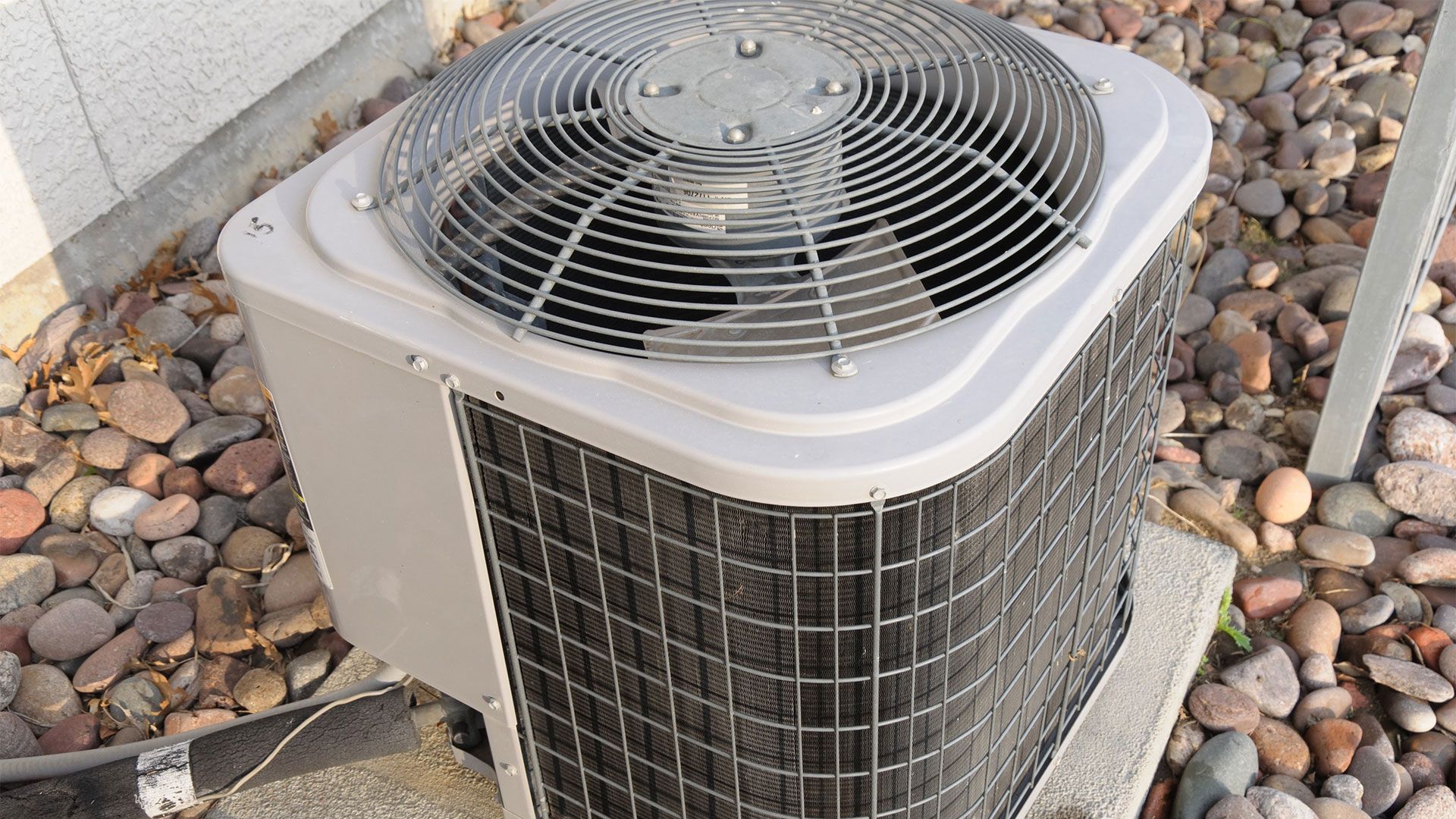 An air conditioner is sitting on top of a pile of rocks.