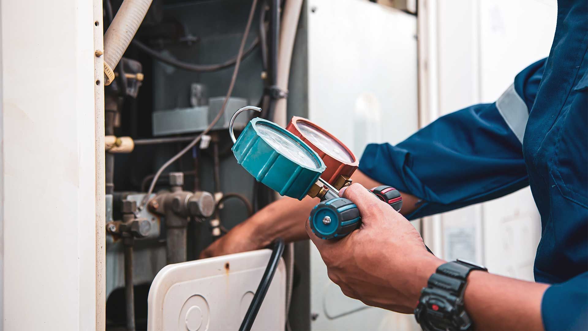 A man is holding a pressure gauge while working on a machine.
