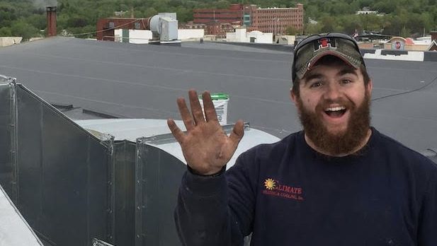 A man with a beard is waving from the roof of a building.