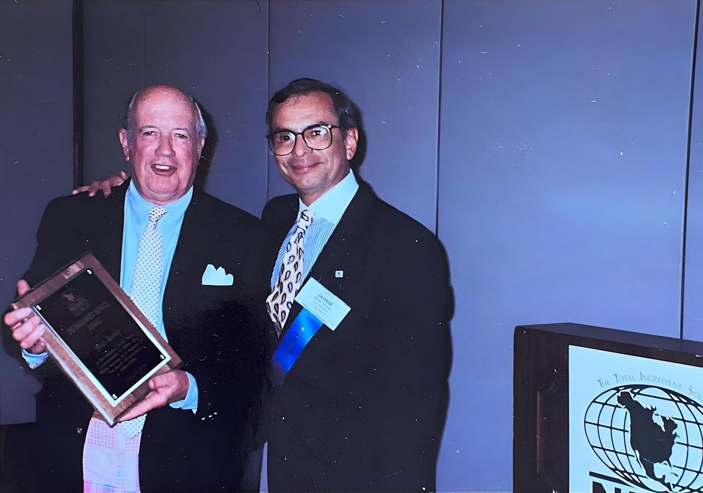 Two men standing next to each other holding a plaque at J.F. Kelly Inc. company party