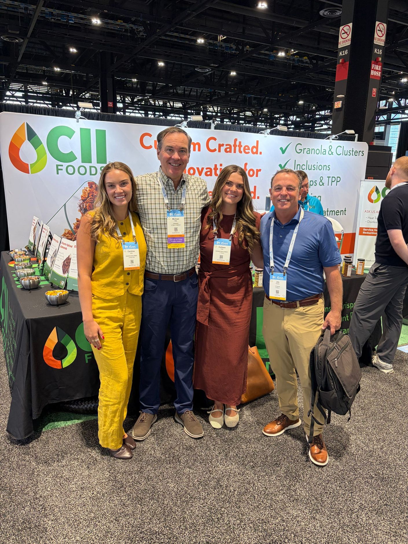 Four people posing at a trade show booth with CII branding, smiling in front of product displays