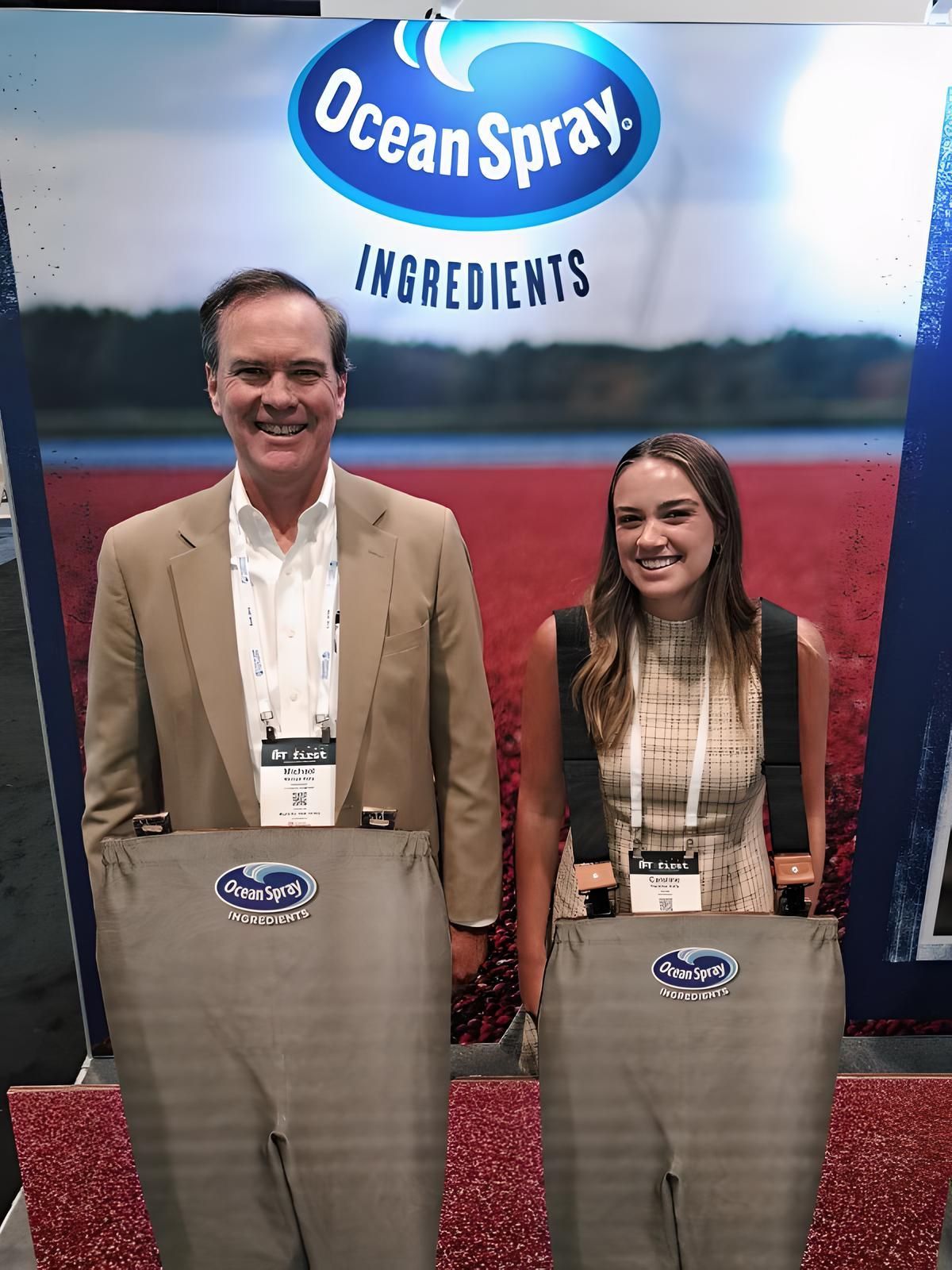 A Michael Kelly and Caroline Kelly are standing in front of a ocean spray sign