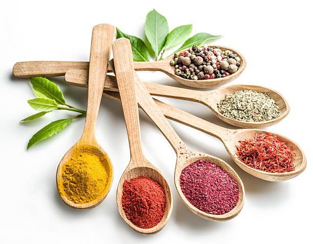 A group of wooden spoons filled with different types of spices