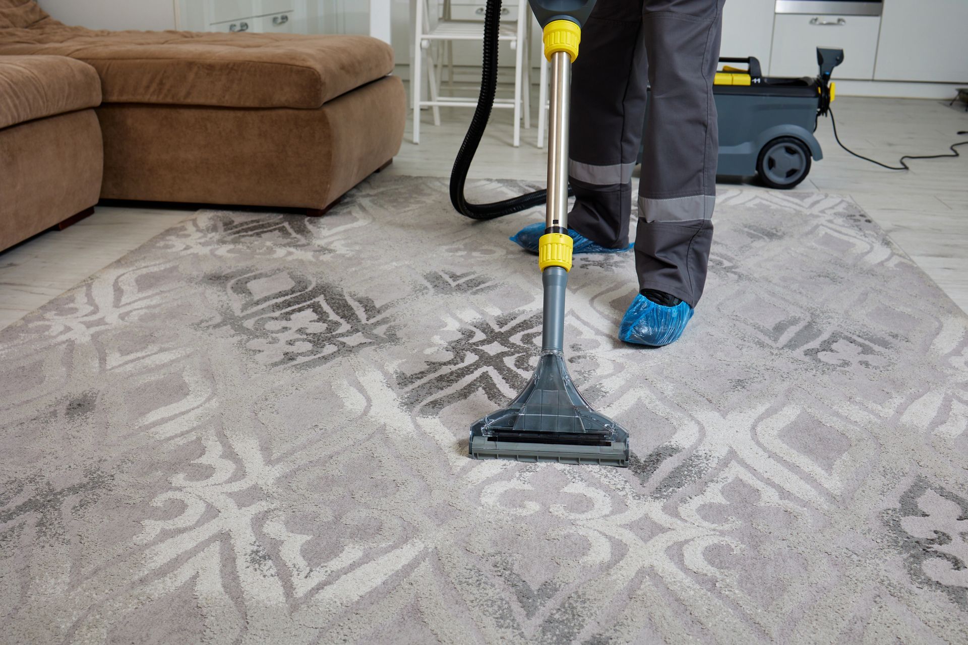 A man is cleaning a carpet with a vacuum.