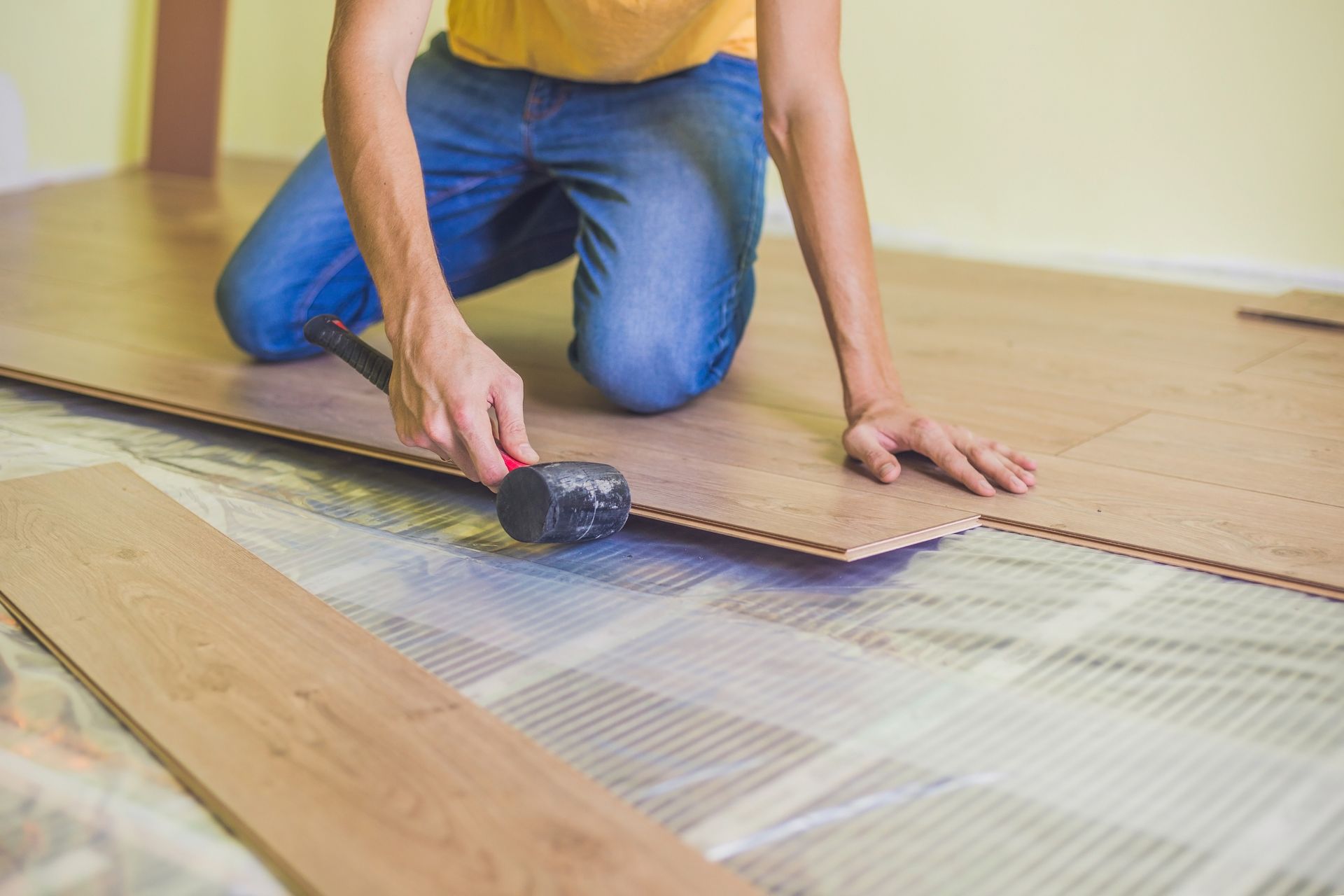 A man is installing a wooden floor with a hammer - Wivenhoe, TAS - Summers Floors Pty Ltd
