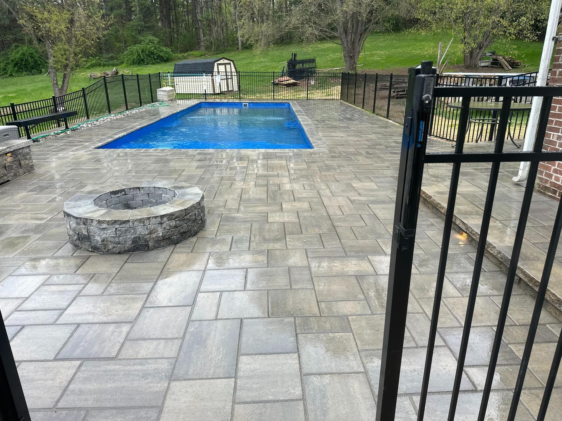 Stone fire pit set into a paver patio beside a pool