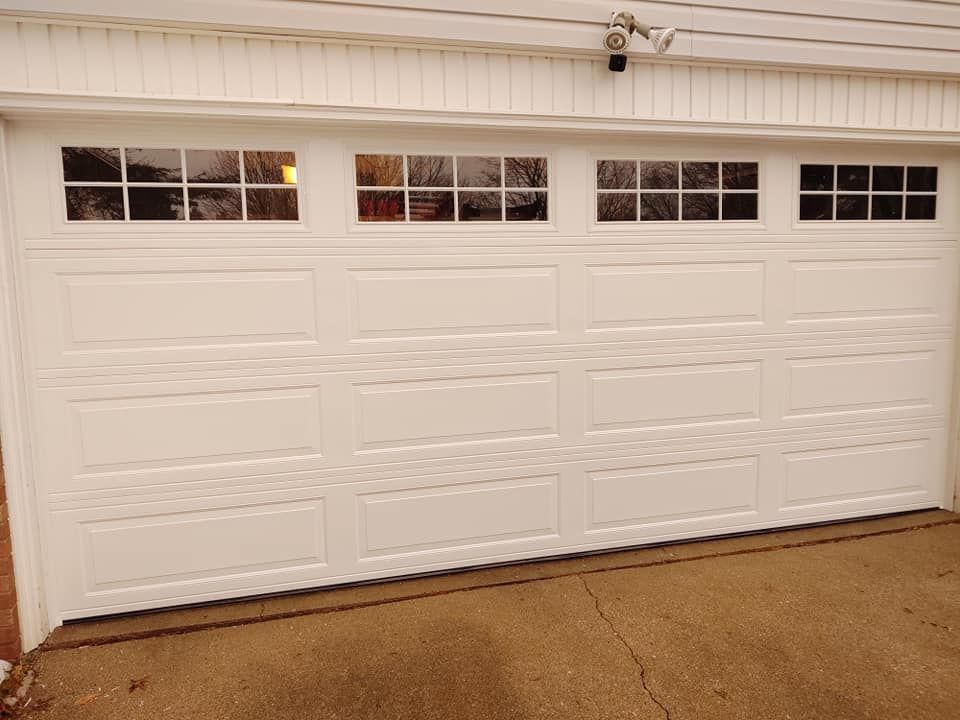 A white garage door with a lot of windows is open.