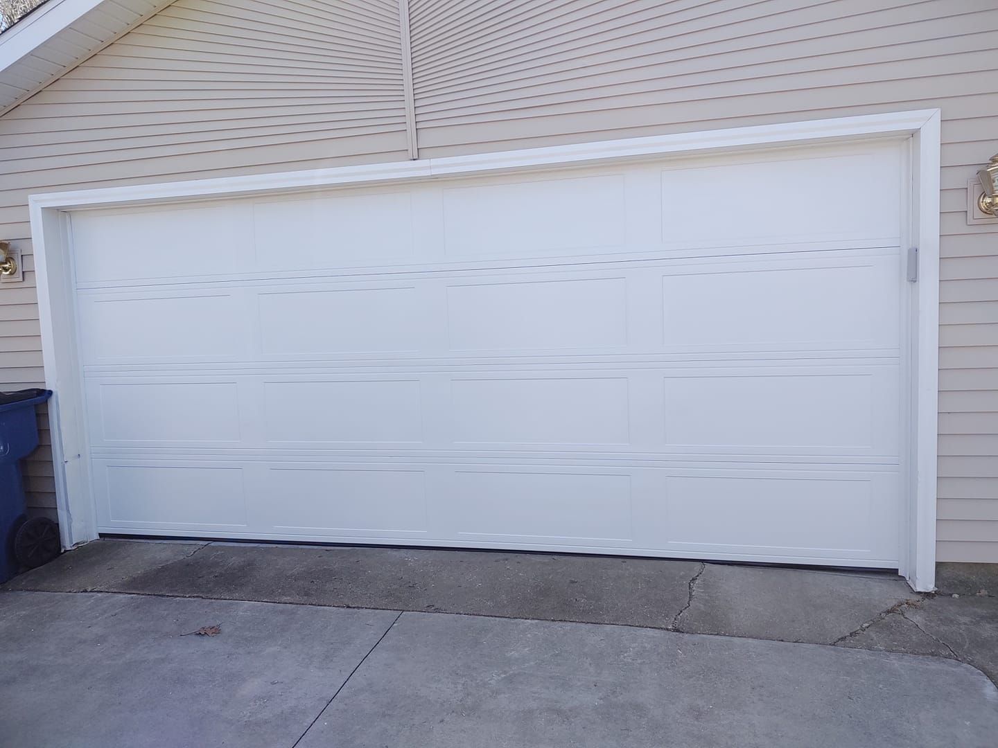 A white garage door is sitting in front of a house.