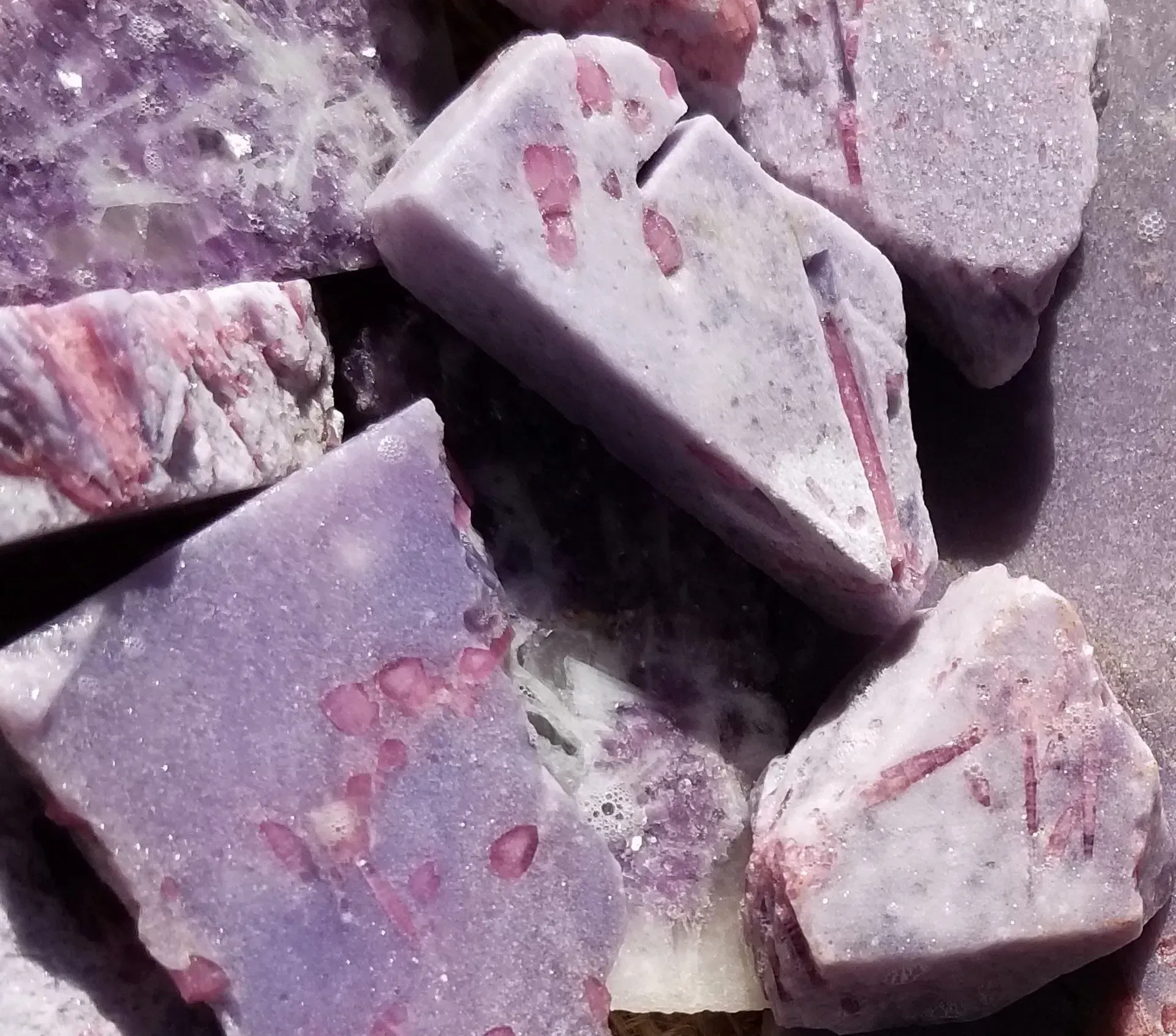 Close-up of rough purple and pink mineral stones with speckled surfaces.
