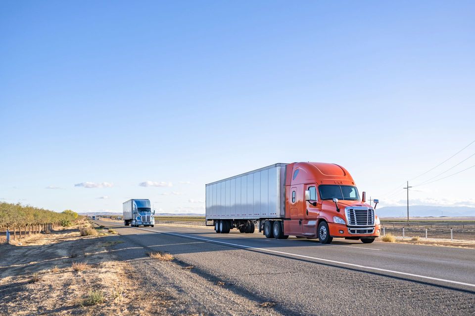Two semi trucks are driving down a highway.