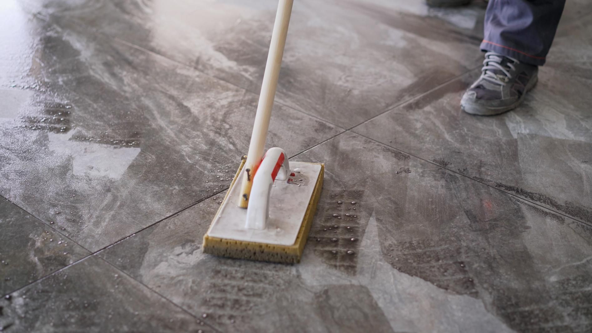 Person mopping a dusty concrete floor with a mop and bucket nearby