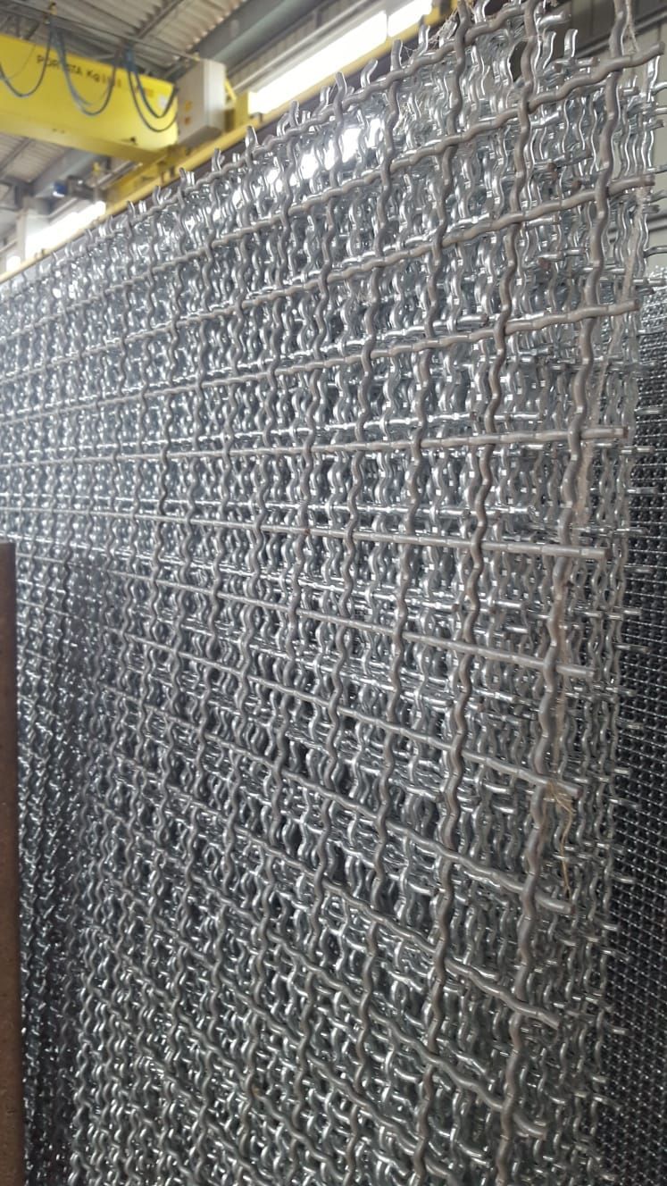 Una grande pila di reti metalliche è posta una sopra l'altra in un magazzino.