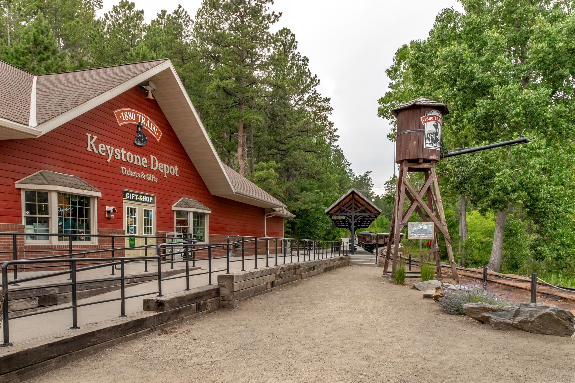 Red lodge-style visitor center with ramp, gravel path, and water tower in a wooded setting