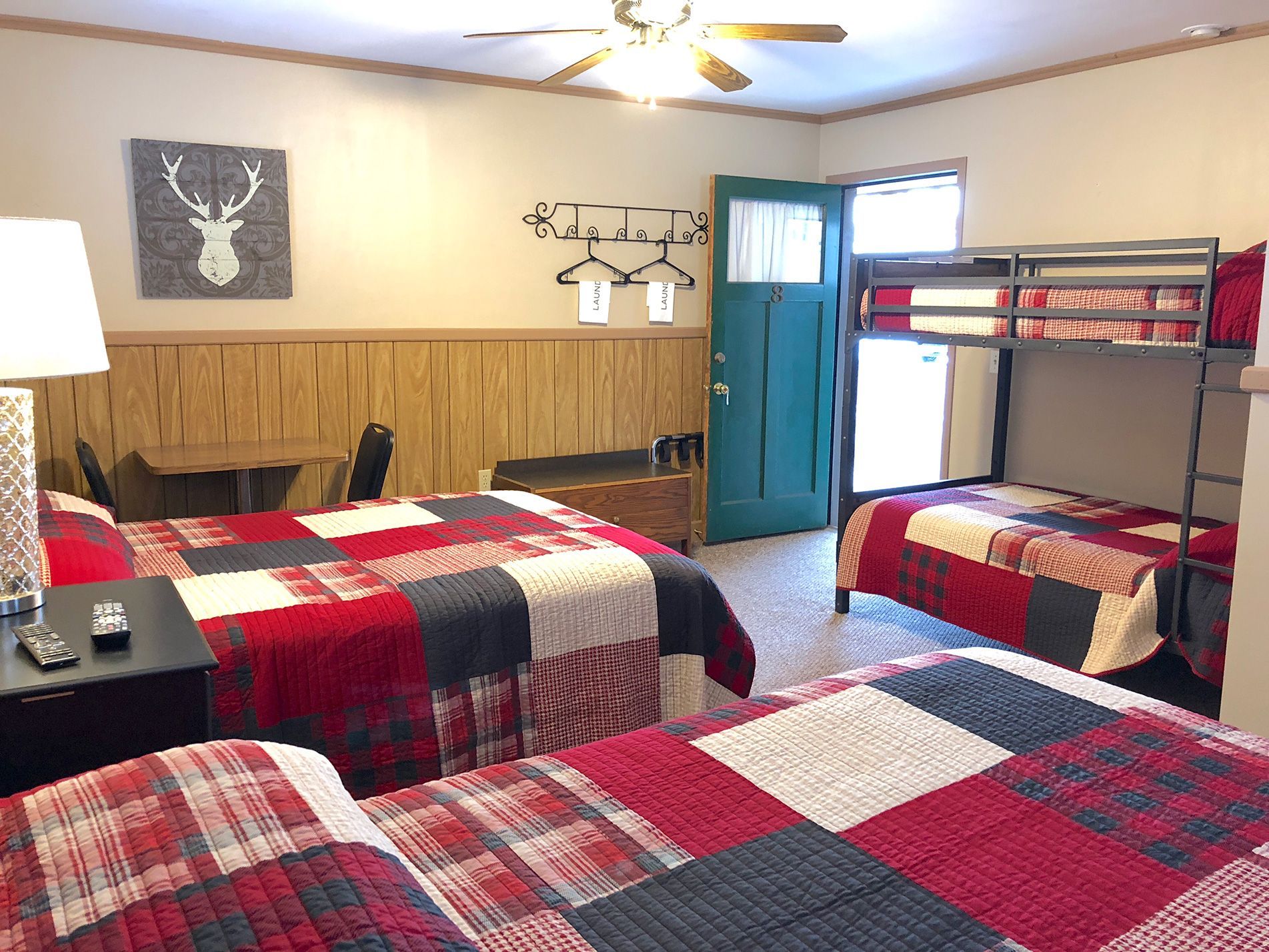 Bedroom with three beds: two queen, one bunk bed, all with red, black, and white patchwork quilts.