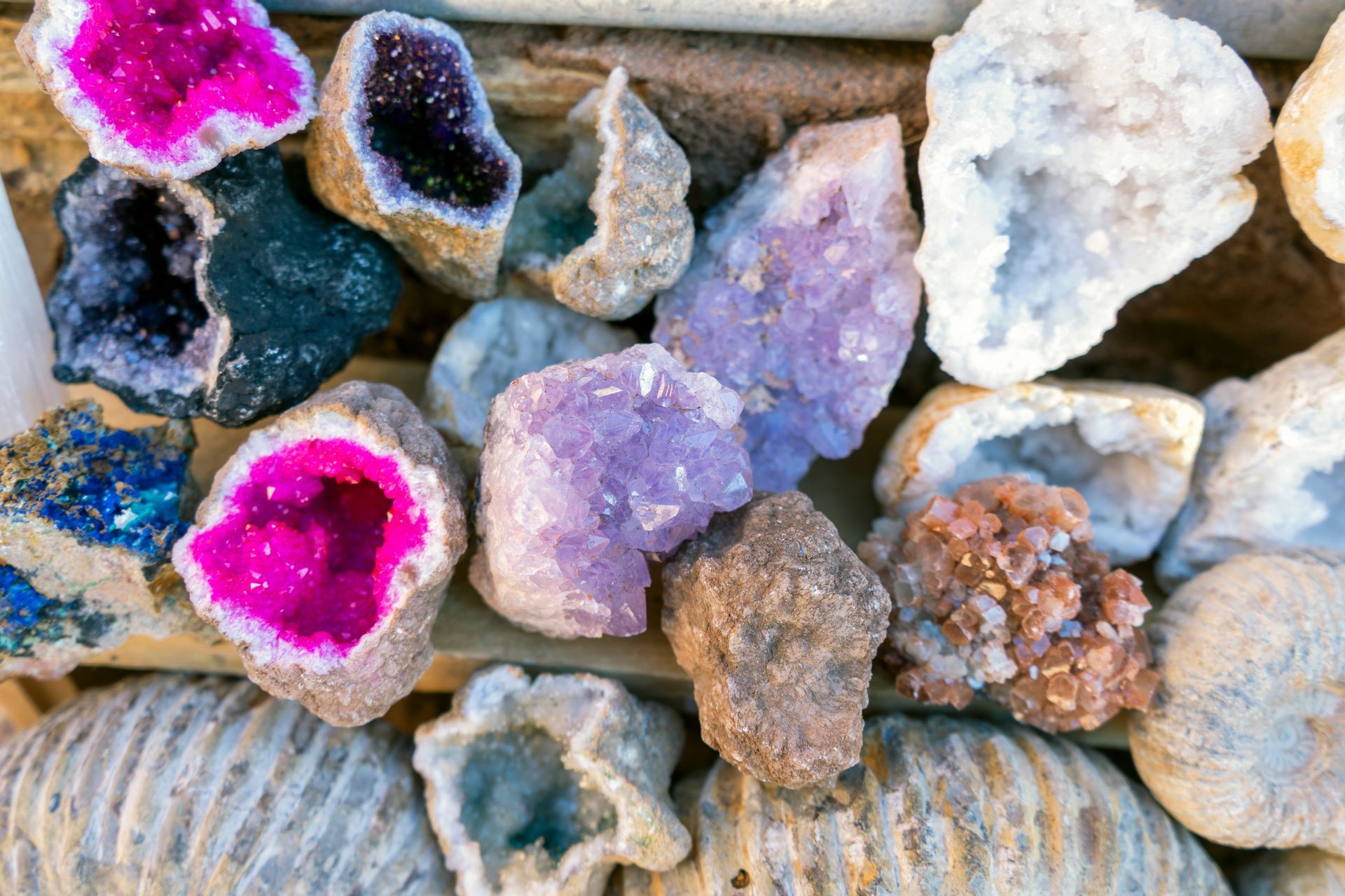 Assorted colorful crystal geodes and mineral rocks displayed in a tray