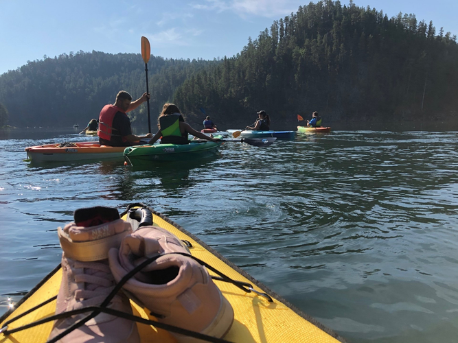 A pair of shoes are tied to the side of a kayak