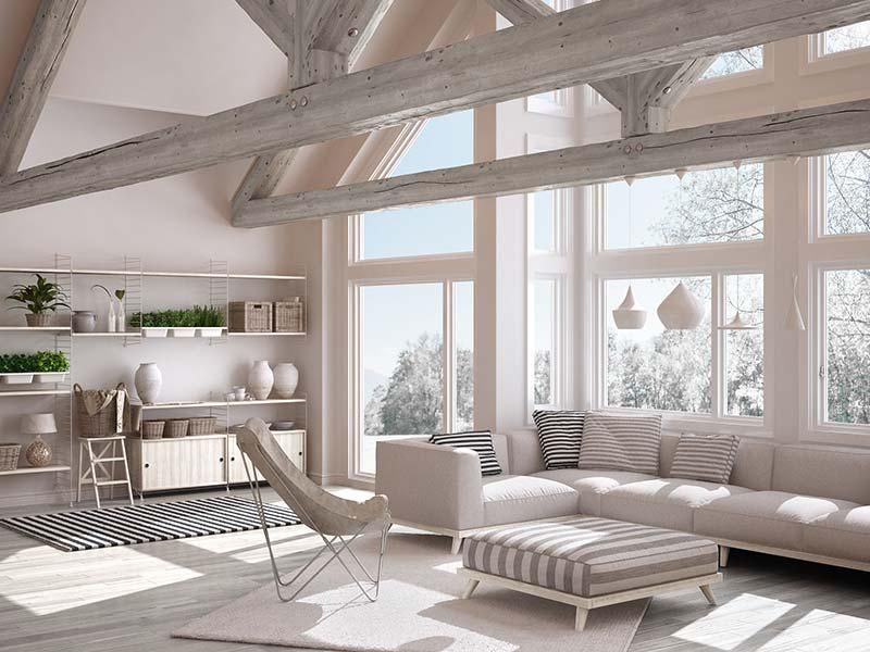 Bright modern loft living room with white beams, large windows, sofa, lounge chair, and open shelving