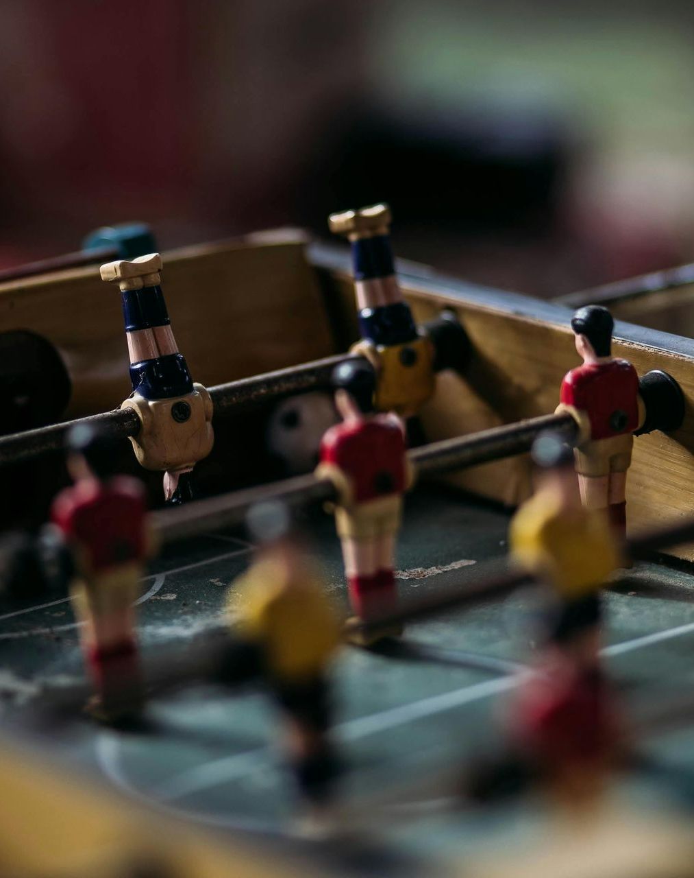 A group of people are playing a game of foosball on a table.