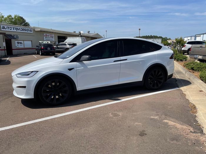 White Tesla Model X with professionally installed window tint, parked outside Auto Trim Designs & Tint in Pearl, MS.