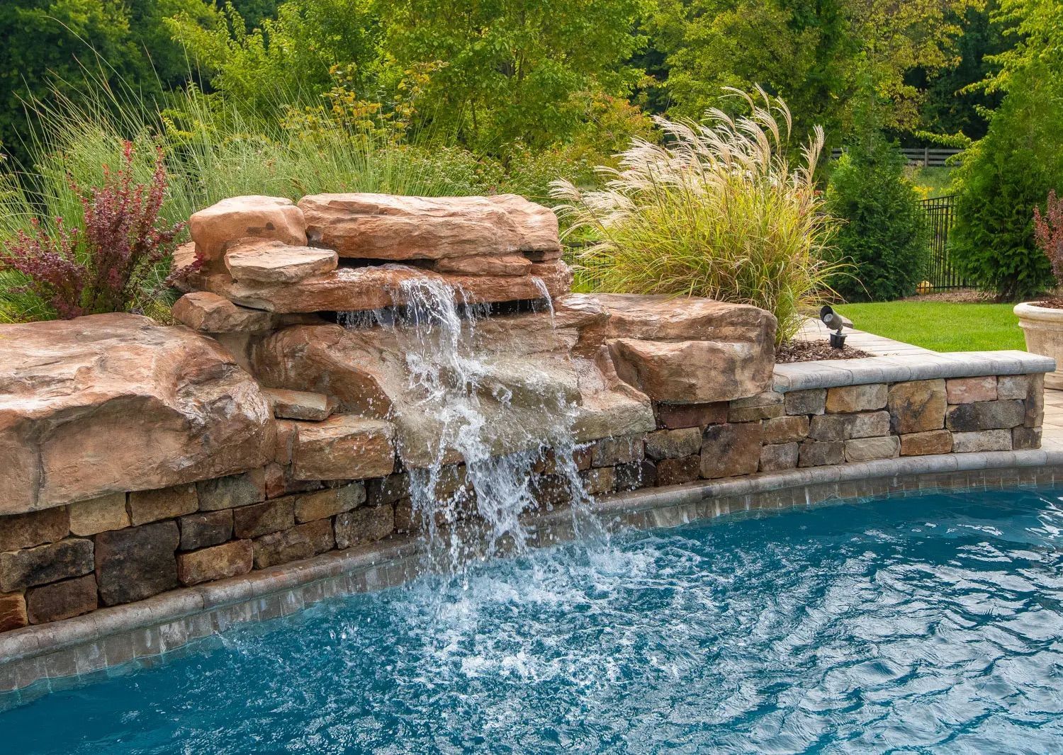 There is a waterfall in the middle of a swimming pool.