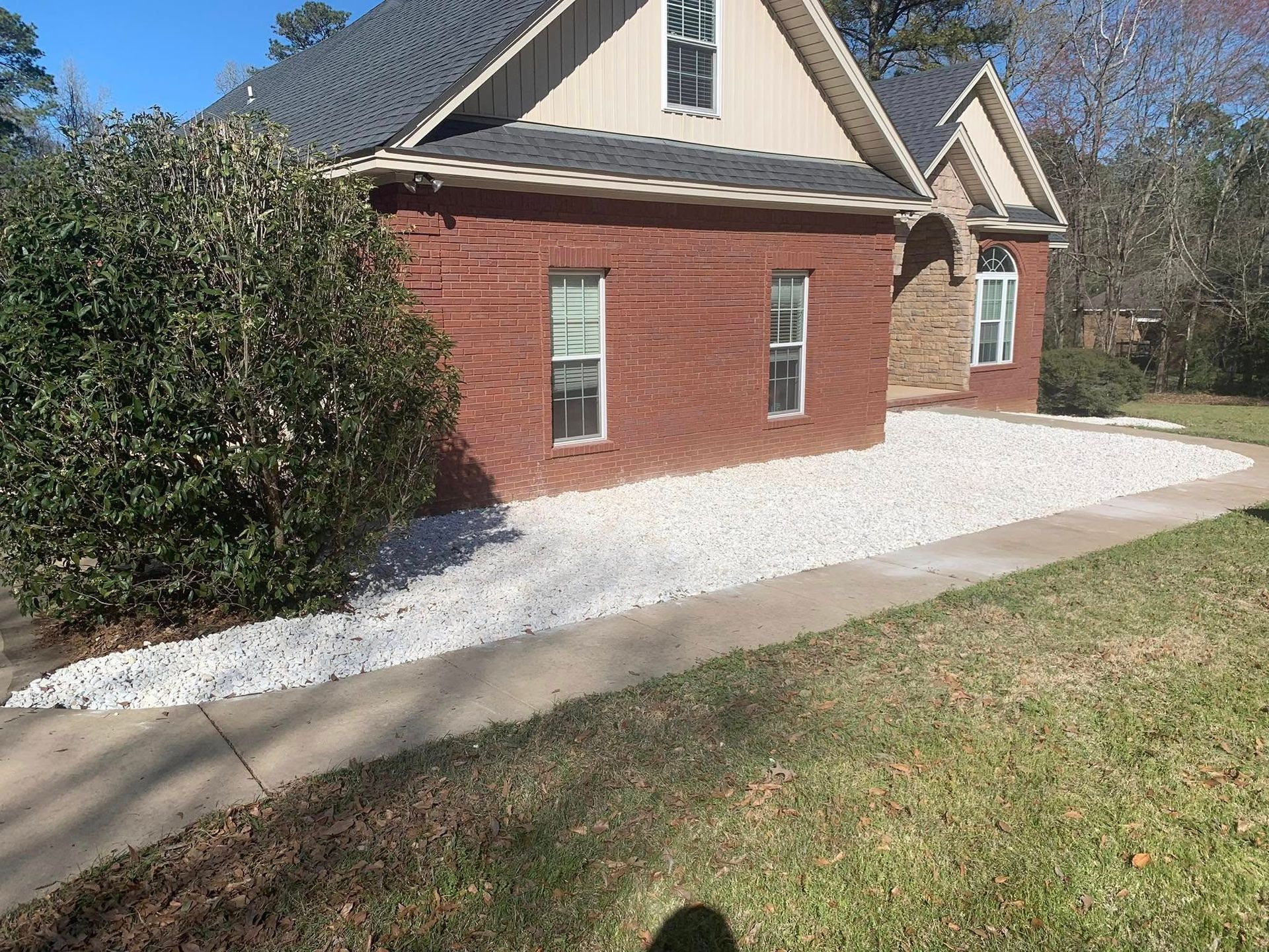 A brick house with a white driveway in front of it.