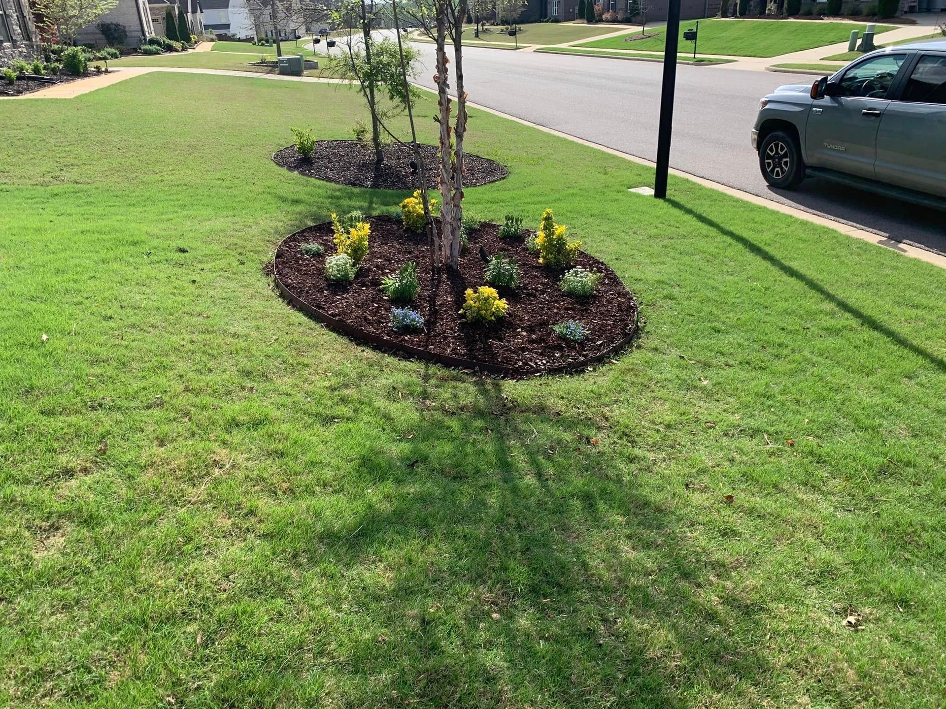 A car is parked in front of a lush green lawn.