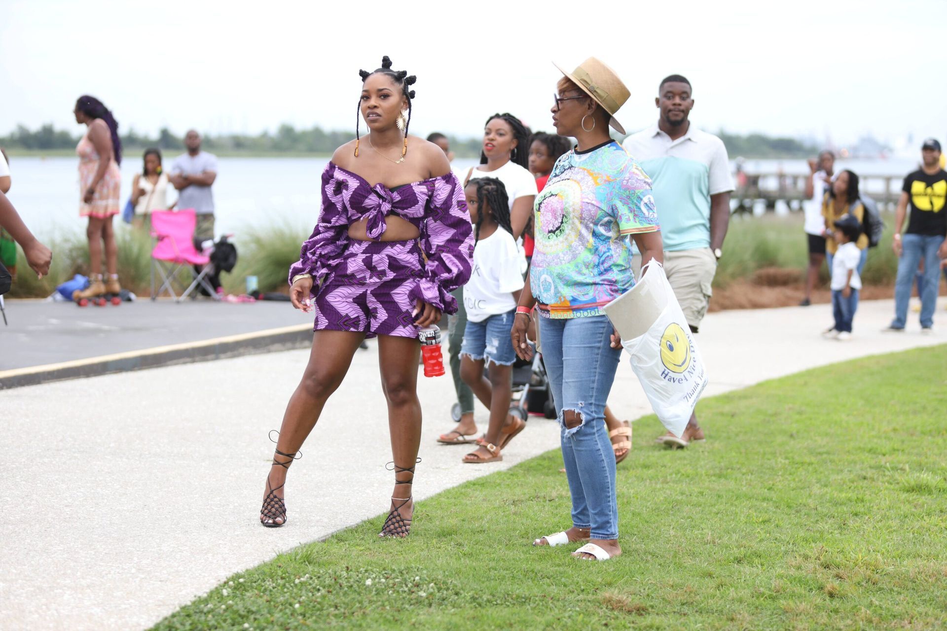 People walking and dancing outdoors near a waterfront during a lively community event