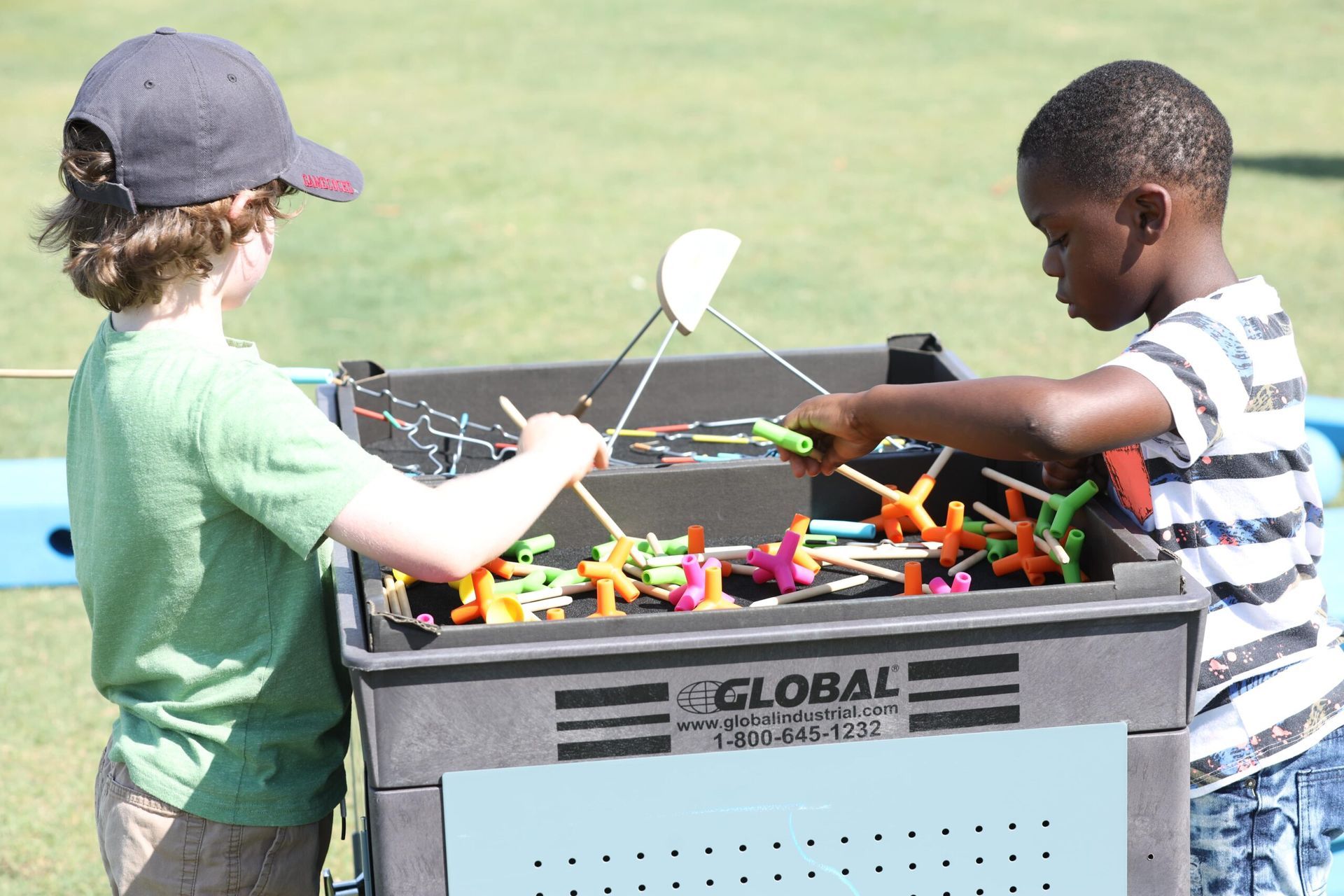 Two children playing with colorful toys at an outdoor bin