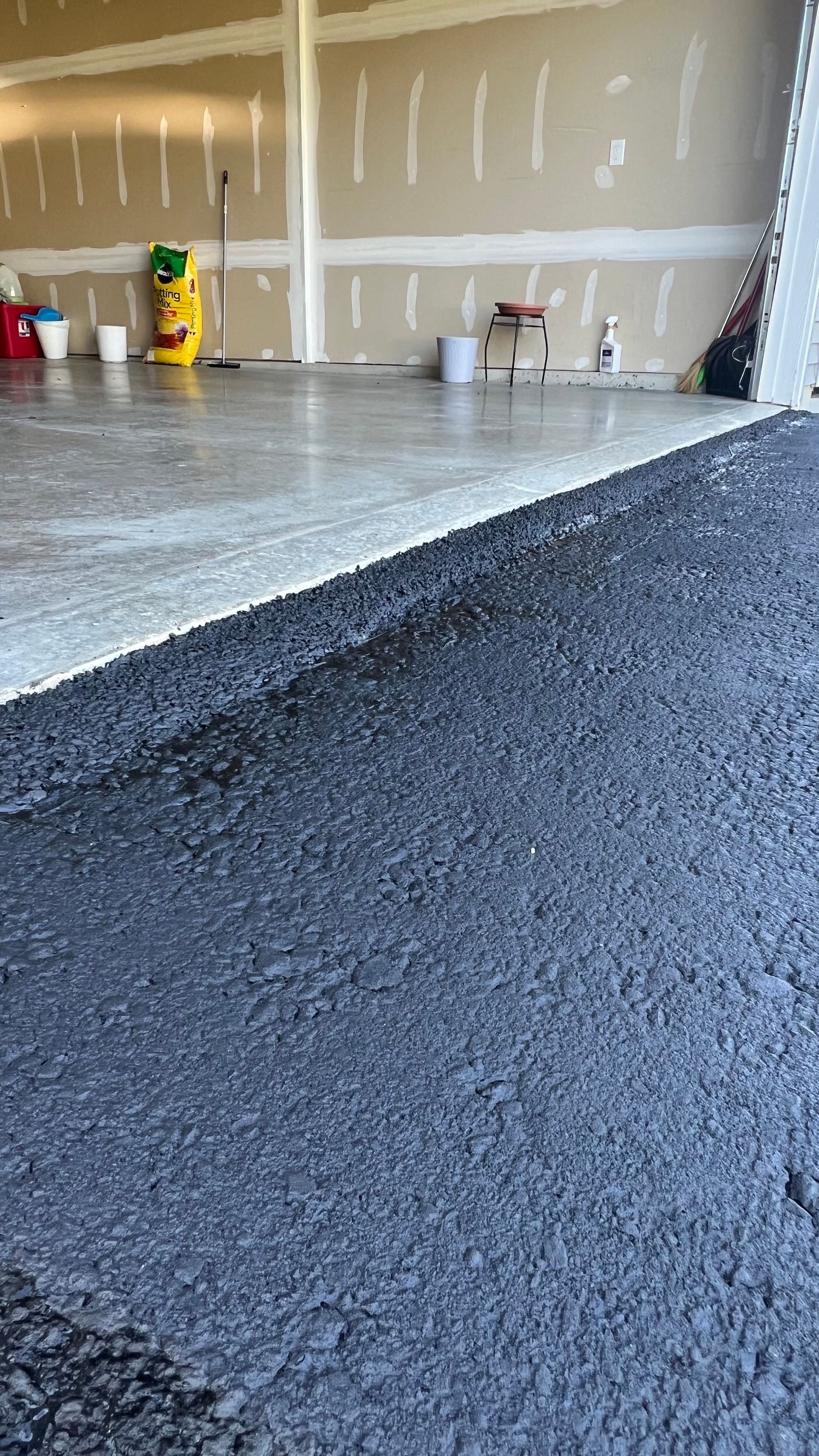 Workers smoothing wet concrete on a floor slab inside a room under construction