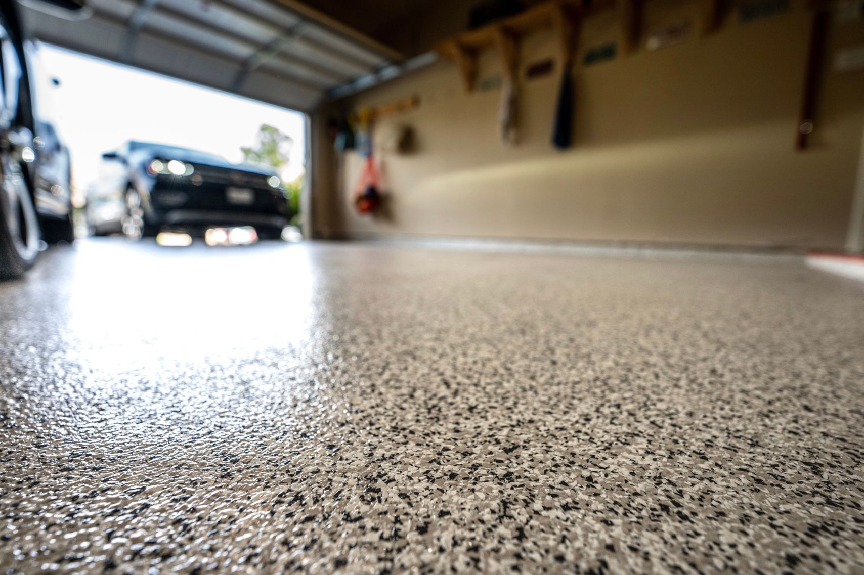 Worker rolling white floor coating over a glossy room floor near a window