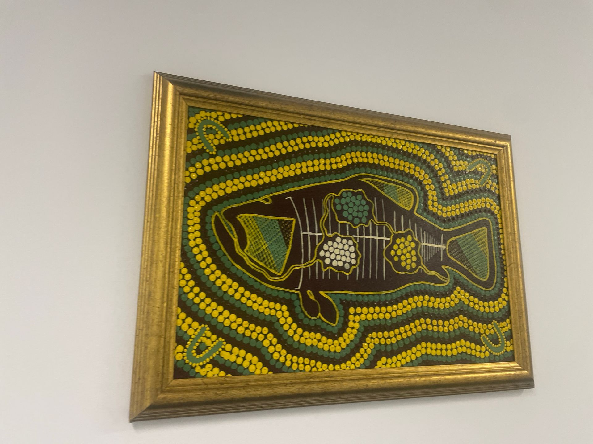 A framed painting of a fish on a wall
