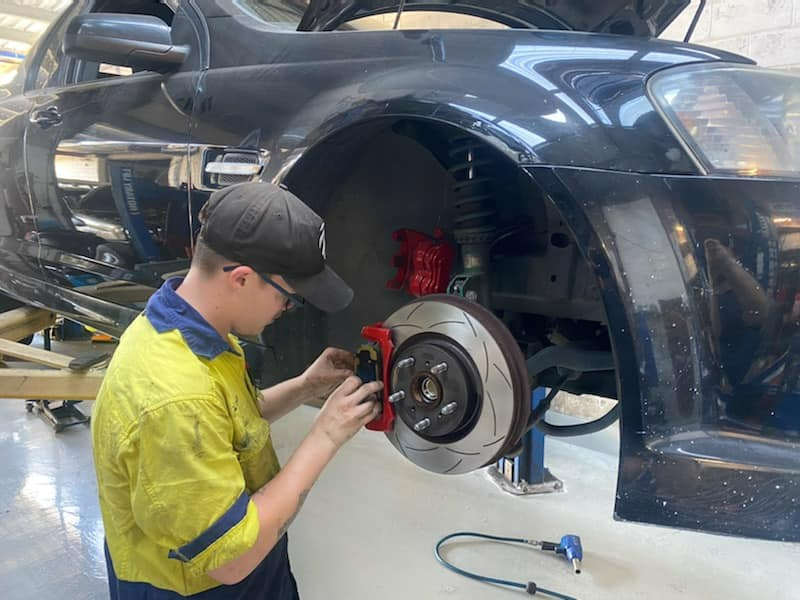 A Man Is Working On A Car In A Garage — Town Automatics 4WD & Mechanical in South Townsville, QLD