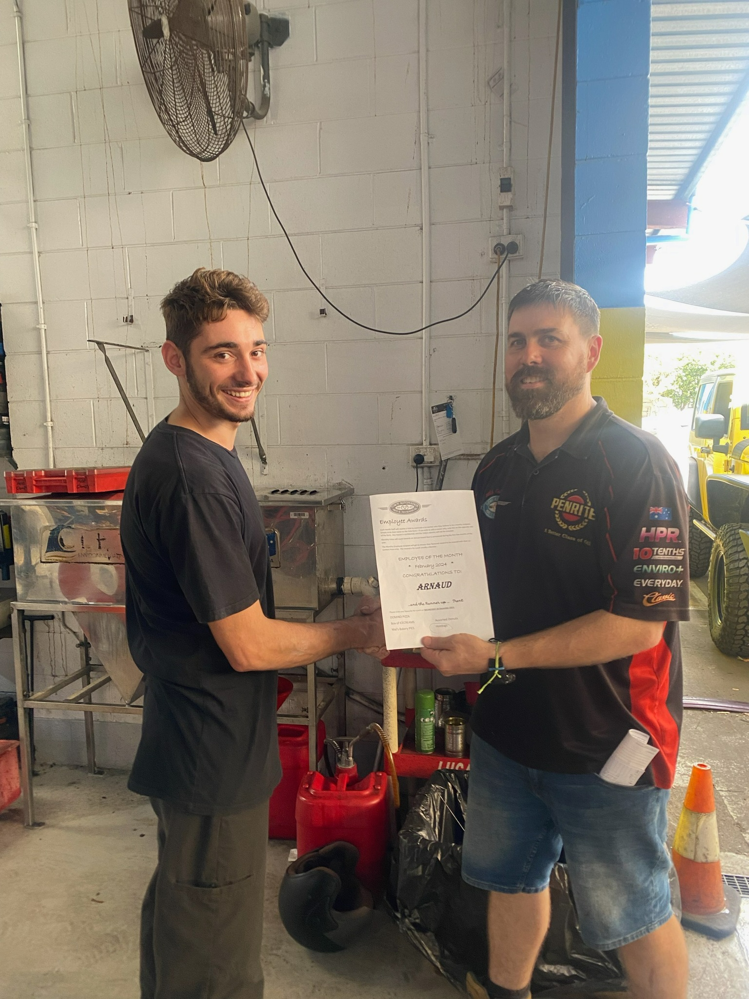 Two Men Are Shaking Hands In A Garage And One Is Holding A Certificate β Town Automatics 4WD & Mechanical in South Townsville, QLD