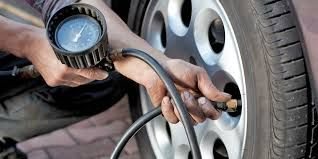 A Person Is Inflating A Tire With A Gauge — Town Automatics 4WD & Mechanical in South Townsville, QLD