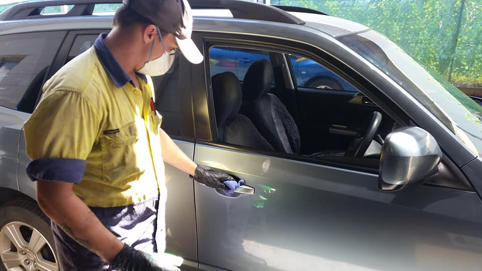 A Man Wearing A Mask Is Opening The Door Of A Car — Town Automatics 4WD & Mechanical in South Townsville, QLD