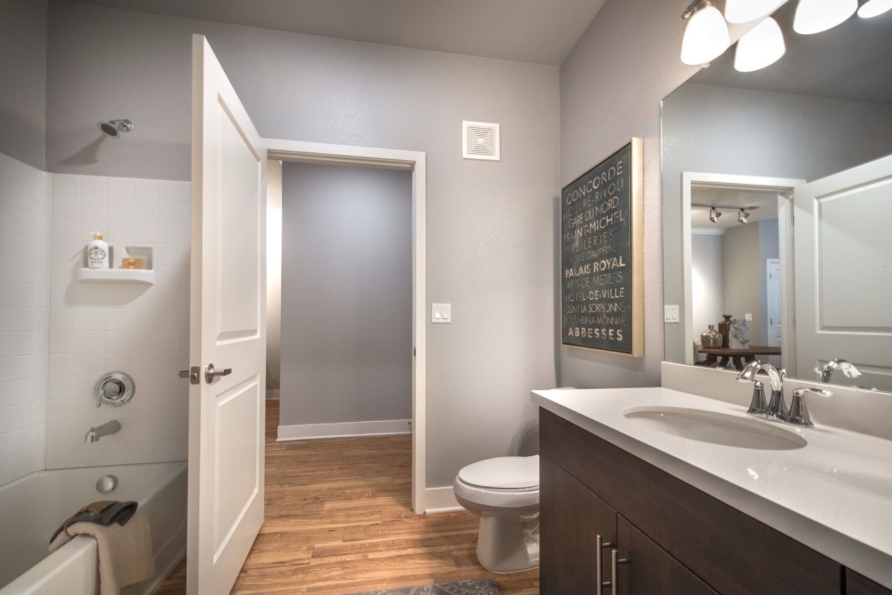 Apartment bathroom with vanity, sink, mirror, toilet, and tub/shower.