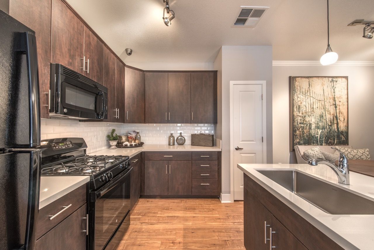 Kitchen with dark wood cabinets, stainless appliances, and an island sink.