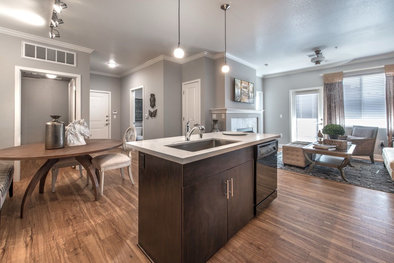 Open-concept kitchen with a dark island, pendant lights, dining area, and living room.