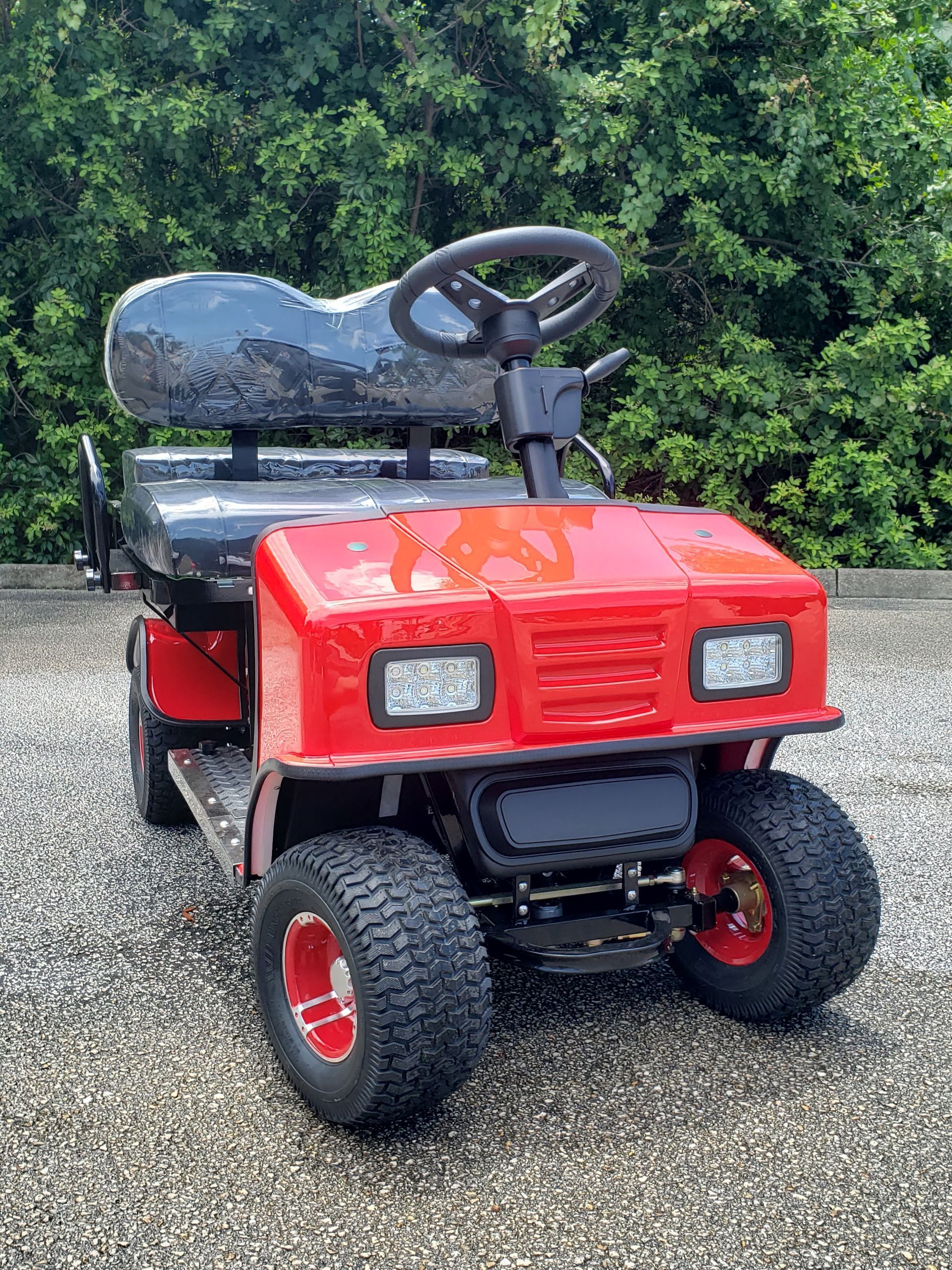 A red golf cart is parked on a gravel road.