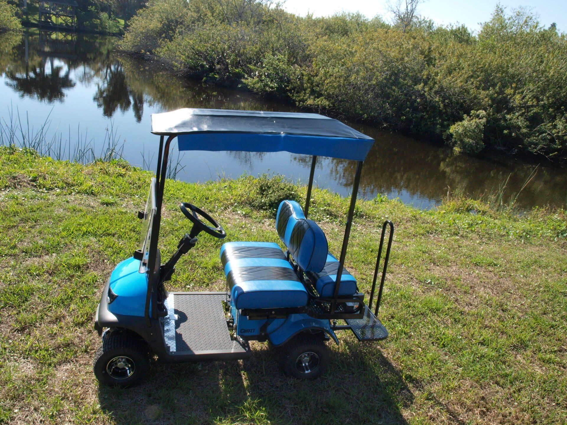 A blue golf cart is parked next to a body of water