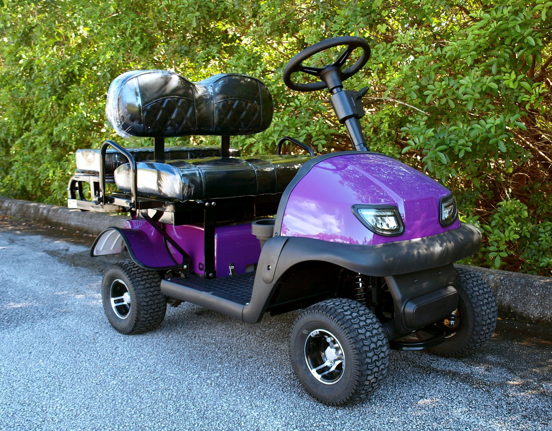 A purple golf cart is parked on the side of the road