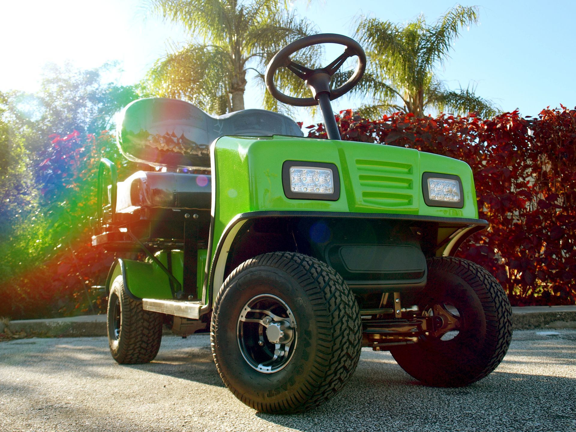 A green Cricket golf cart is parked on the side of the road.