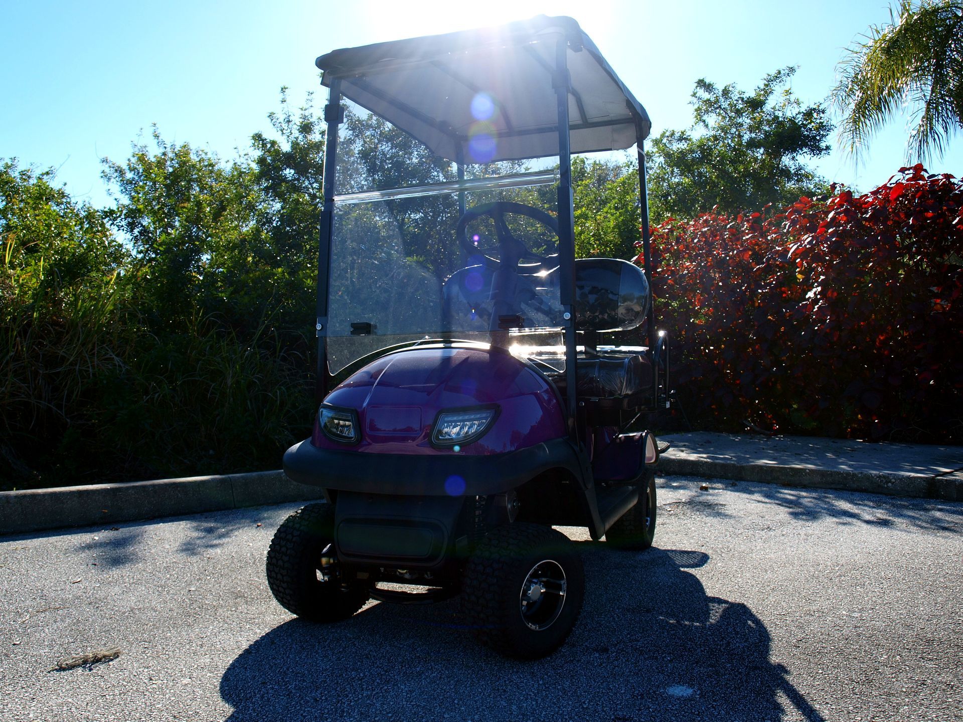 A purple golf cart is parked in a parking lot