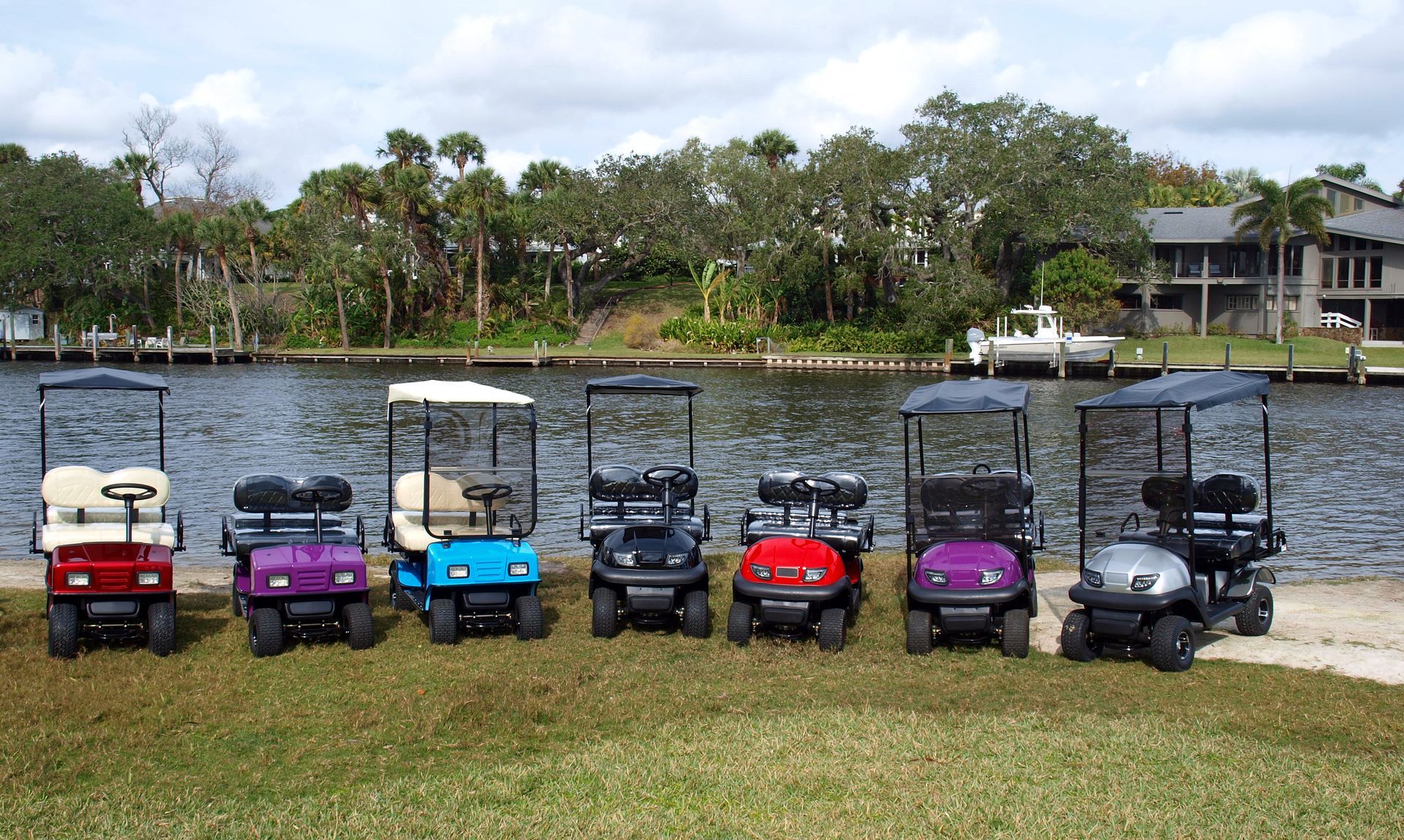 A row of golf carts are parked in front of a body of water