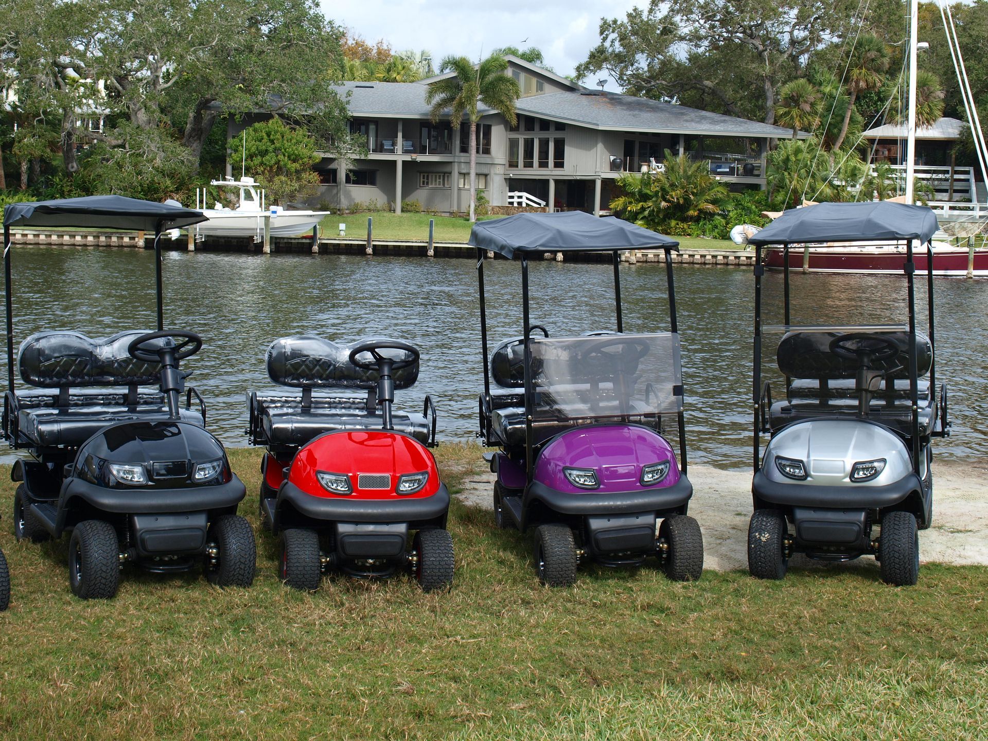 A row of golf carts are parked in front of a body of water