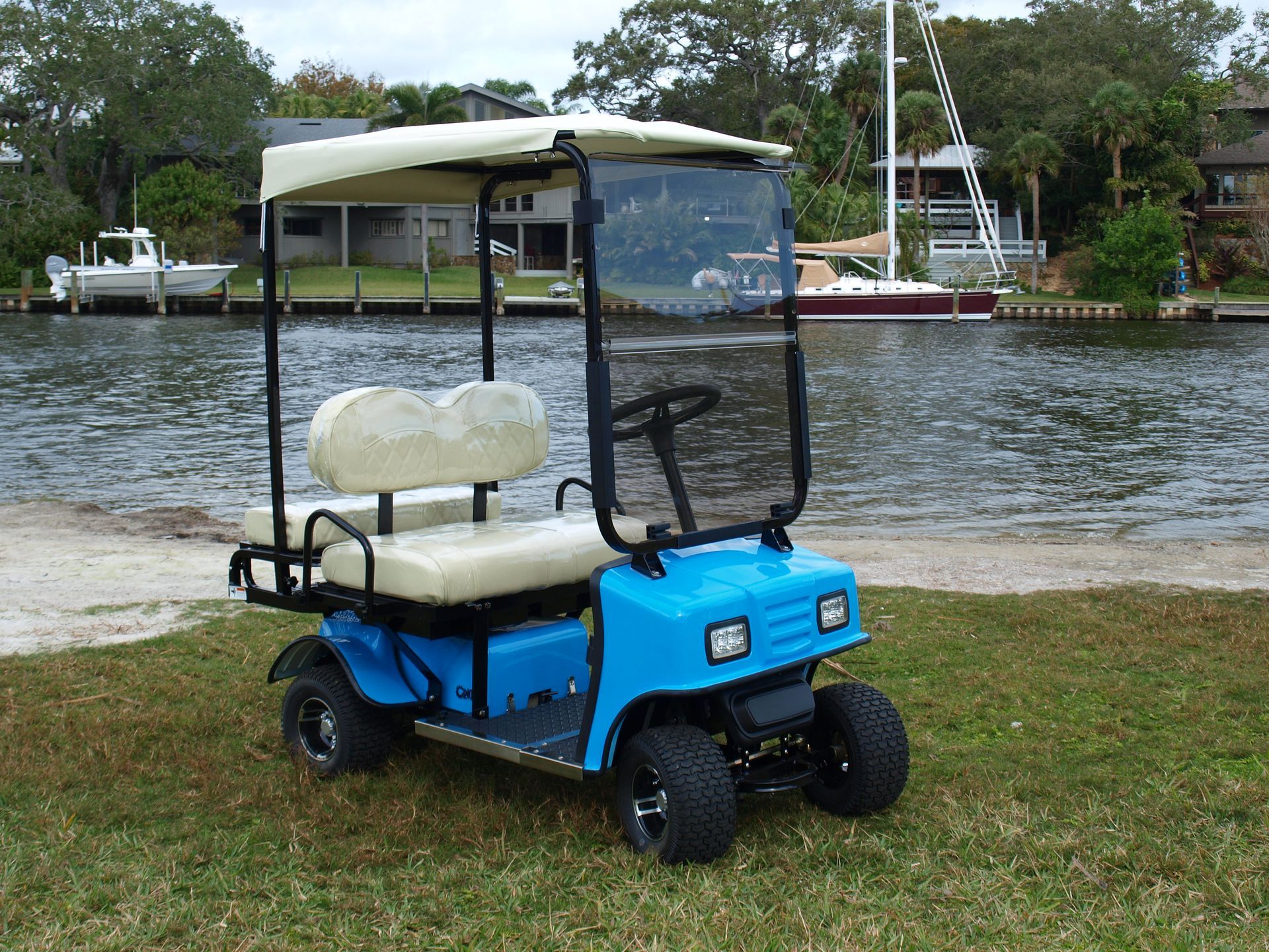 A blue golf cart is parked next to a body of water